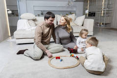 一个有两个小孩的年轻家庭正坐在客厅的地板上。在一起的快乐时光爱与柔情.