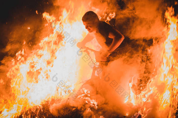 骑山地自行车的疯狂的骑车人骑在篝火、火花和火焰中，他们在一个真实的事件中从骑自行车的人身边走过。骑自行车的人玩明火很危险.
