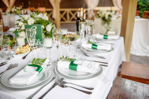 桌上摆设有晶莹的玻璃杯,盘上有白色<strong>餐巾</strong>纸和餐具,复制空间.婚礼接待处的位置。餐桌在餐馆举行婚宴