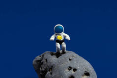 在深蓝色背景的月球石上，可爱的小型宇航员。最小空间日卡.