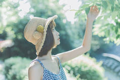 一个戴着帽子和草帽的年轻漂亮女子在花园里摆姿势的画像