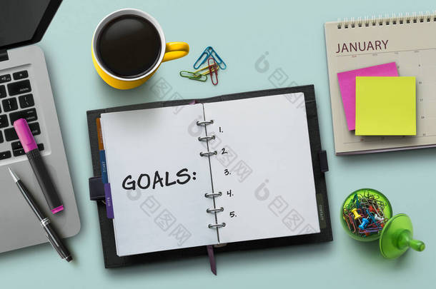 5.新年目标、决议或行动计划概念。桌面上有笔记本、日历、咖啡、工厂和文具的笔记本。蓝绿色背景下的输入法副本或文本的平铺(顶部视图)记事本.
