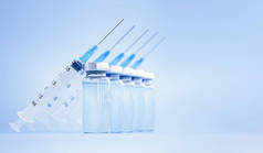 疫苗瓶和注射器在蓝色背景上排成一排