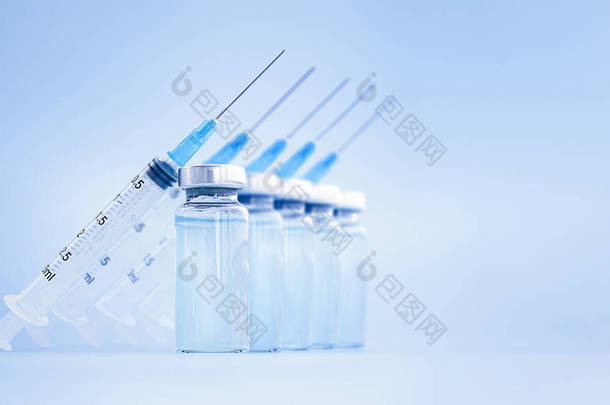 <strong>疫苗</strong>瓶和注射器在蓝色背景上排成一排