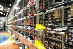 抽象模糊运动鞋在货架上的运动鞋商店背景。许多运动鞋在超级市场的货架上销售，其影响模糊不清.