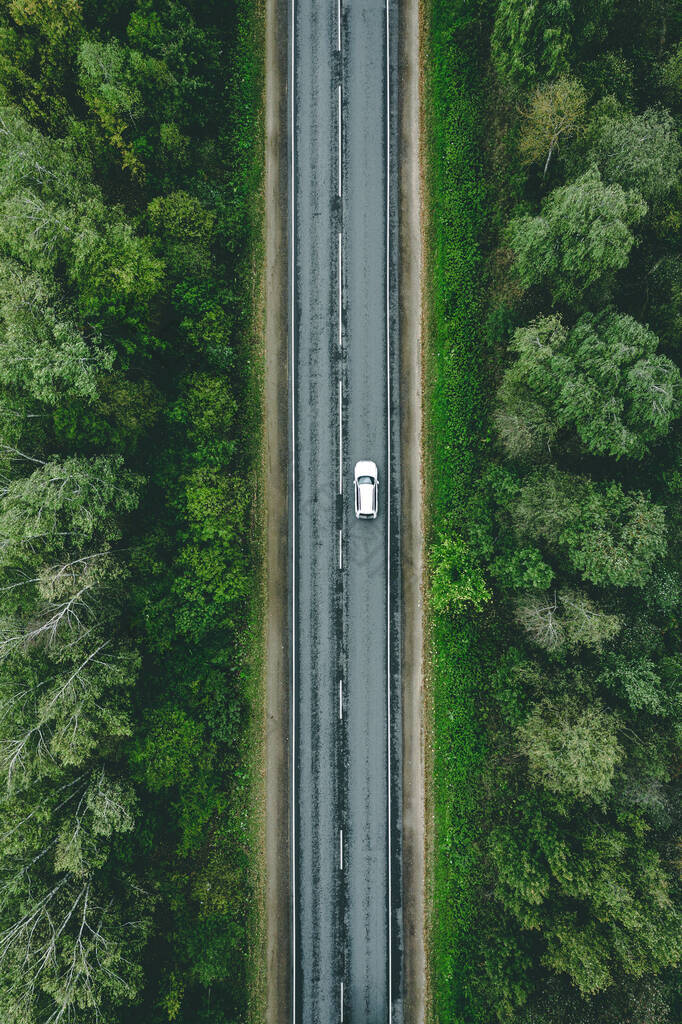 乡村道路的空中景观，汽车驶过绿色的夏季森林和玉米地