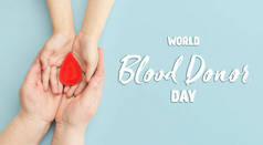 女人的手把一滴血放在蓝色的背景上.献血、输血、世界血友病日的概念。世界卫生日。展示.banner