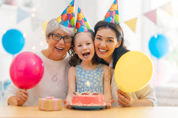 那孩子在吹灭<strong>蛋糕</strong>上的蜡烛.奶奶、妈妈和女儿在庆祝<strong>生日</strong>.