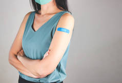 注射柯罗纳威疫苗后，身穿绿色无袖T恤、头戴布制口罩、腋下打着石膏绷带的亚洲妇女的剪影.