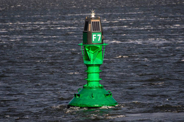 阳光明媚的春天，明亮的绿色浮标在深蓝色的北海中游动
