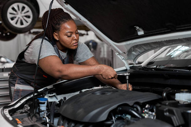 在汽车修理厂修理厂的车篷下工作的黑人女技师