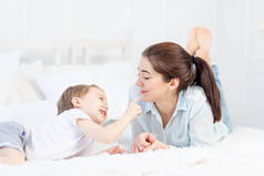 母亲和婴儿在家里床上玩耍，家庭和亲子关系的概念