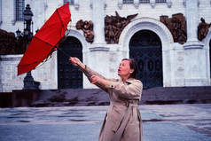 Adult woman with a red umbrella in the rain and strong wind