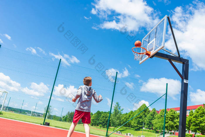 男孩在操场上打篮球。夏天，男孩在操场上的红场球赛上打篮球.