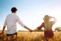 年轻快乐的夫妇拥抱在麦田上，夕阳西下。一起享受时光。青年、爱情和生活方式的概念.