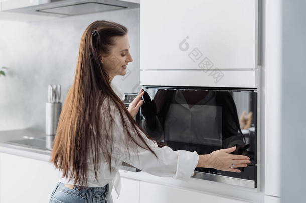 女人们在家里做饭的时候，用新的现代化厨房用具给家人做饭，笑着关上微波炉的电门