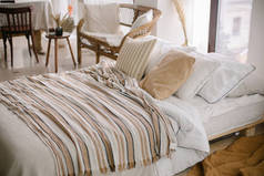 舒适的卧室。床与枕头和条纹毛毯在舒适的轻便卧室