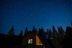 美丽的夜景，森林中的房子映衬着喀尔巴阡山脉星空的映衬