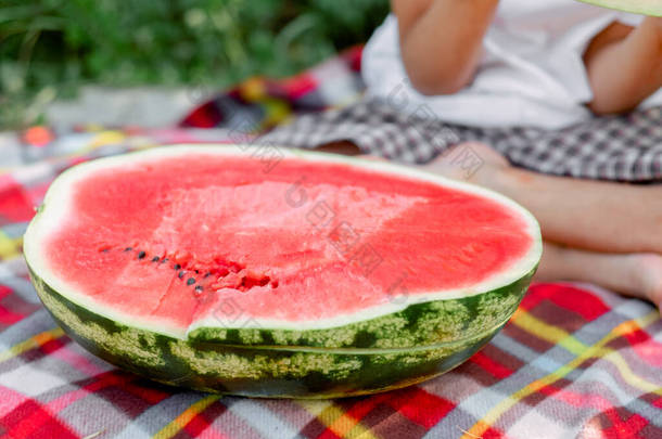 野餐时吃半个大西瓜，特写。夏天的心情<strong>鲜红</strong>多汁的西瓜.甜的大浆果。夏天新鲜的水果。西瓜野餐