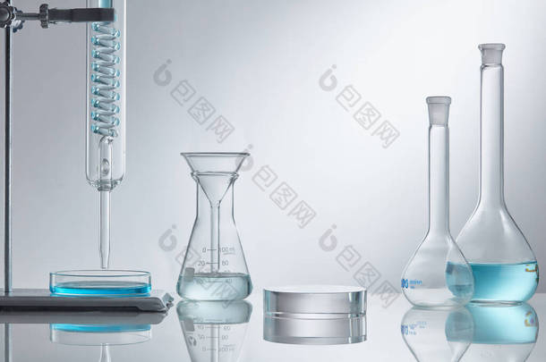 在实验室设备的现代玻璃基座上展示化妆品.实验室玻璃设备，白色底座上有蓝色水成份。研究与开发化妆品概念