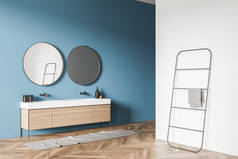 简约的浴室内部与虚荣，两个在趋势圆形的镜子蓝色的墙壁和毛巾架附近的白墙分区。木制瓷砖地板。现代室内设计的概念。3d渲染