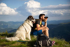 英俊潇洒的男人和白狗在自然界中用双筒望远镜慢行