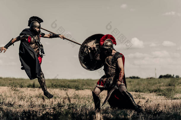 两个身穿战斗服的古希腊<strong>战士</strong>或罗马<strong>战士</strong>，在天空的衬托下，在草地上，用矛和剑战斗.