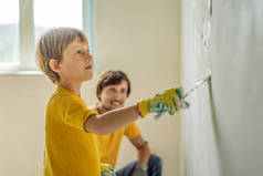 男人和他的儿子在家里修理，他教孩子们用手拿着铲子在墙上贴石膏