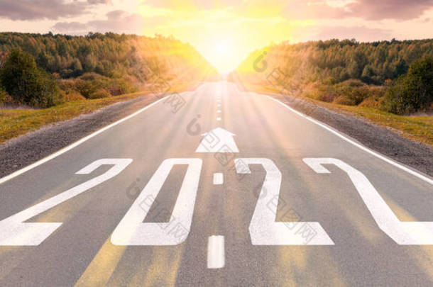 空旷的沥青路面和2022年新年的概念。在通往2022年目标的空旷道路上开车，夕阳西下。2022年写在公路上，箭头在空旷的沥青路面上。2021-2022年远景构想.