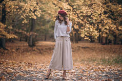 秋天公园里黑发女子的画像。法国风格。身穿贝雷帽和条纹衬衫的妇女