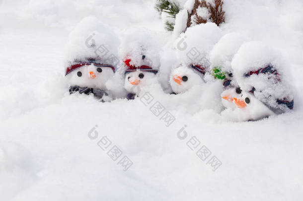 五个可爱的小雪人，头戴帽子，头戴围巾，头戴胡萝卜鼻子，头戴新雪。冬季雪地风情