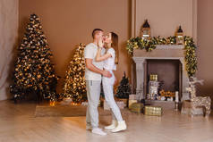 在圣诞树旁和壁炉旁，一男一女穿着家居服接吻