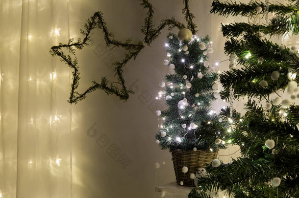 可爱的<strong>盆栽</strong>圣诞树，点缀有金属丝微光和白色装饰小球，夜间在室内发出嗡嗡声或感觉球的花环。<strong>墙上</strong>的星形花环。案文的空间.