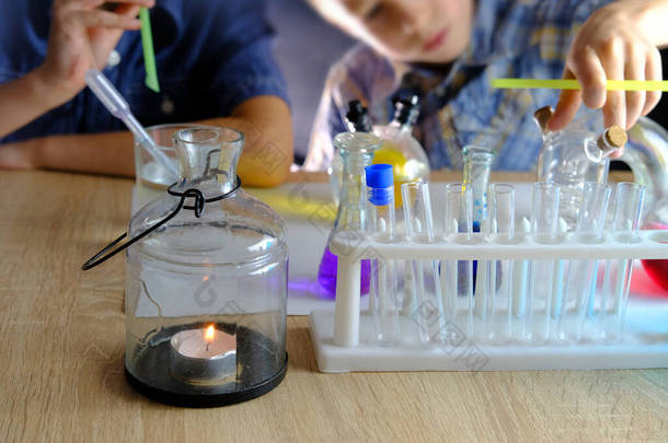 两个7-9岁的孩子，<strong>小</strong>学</strong>生，做化学<strong>实验</strong>，把彩色液体倒入玻璃瓶，混合颜色，学校教育理念，亲自动手学习化学
