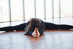 身穿黑色运动服的胖女人伸懒腰躺在地板上.