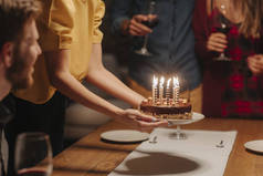 把生日蛋糕放在桌上的面目全非女人的手.