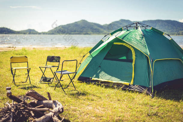 野营帐篷与<strong>熄灭</strong>的篝火在绿色的领域草甸, 湖和山的背景。野餐和旅行的概念。自然主题.