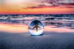 波兰莱巴附近的斯洛宾斯基国家公园海滩上美丽的日落。通过玻璃水晶球（透镜球）进行折射摄影。野生的，原始的自然.