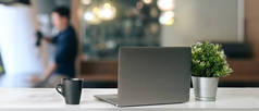 办公室办公桌上放着装有咖啡杯和工厂的开放式笔记本电脑的现代工作场所.