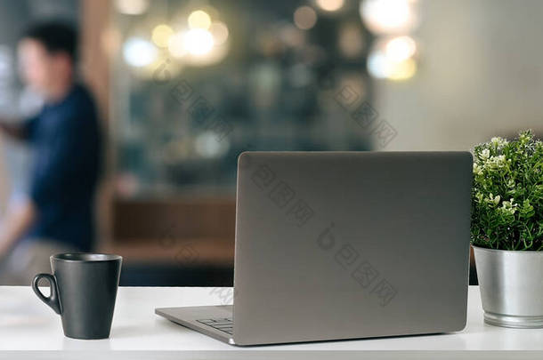 办公室办公桌上放着装有咖啡杯和工厂的开放式笔记本电脑的现代工作场所.