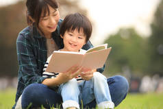 亚洲母亲在暑期公园给儿子读书