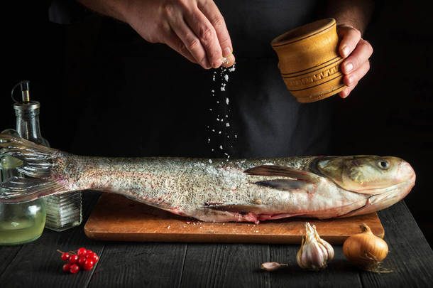 厨师准备新鲜的鱼、生鱼片、鲤鱼、撒盐.准备烹调鱼的食物。餐厅<strong>厨房</strong>的工作<strong>环境</strong>.