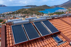 太阳能热水器安装在房屋的瓷砖屋顶上，以便节约用水。很多大水箱.
