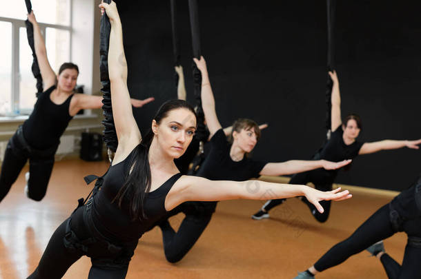 一群身穿黑色运动服的活跃的女运动员在体育馆里做体操。蹦极跳进体育馆.
