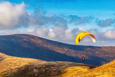 秋天的一天，人们试图用五彩缤纷的降落伞在蓝天白云的映衬下进行滑翔伞探险
