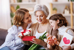国际妇女日快乐。女儿和孙女在家里送花给奶奶庆祝母亲节