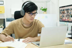 年轻的男生在家里学习。他用笔记本电脑上网学习