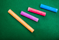 四个块粉笔不同的明亮的颜色而且不同的长度谎言绿色背景