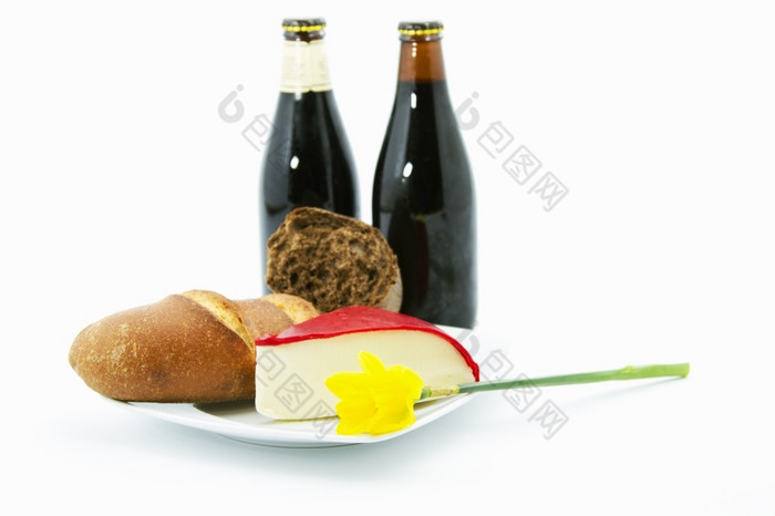 两个瓶黑暗啤酒是放置与整个粮食面包红色的皮奶酪白色板真正的国家午餐减轻了单黄色的水仙花