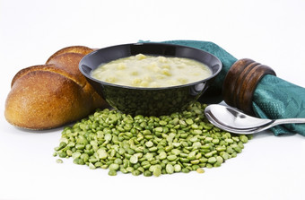 分裂(2008年)汤黑色的碗与新鲜的面包面包绿色餐巾而且棕色（的）木餐巾环<strong>干豌豆</strong>成分对白色背景